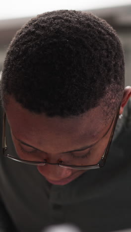 black man with glasses works at table closeup. black student studies education sources in library reading hall. african american guy in coworking premise