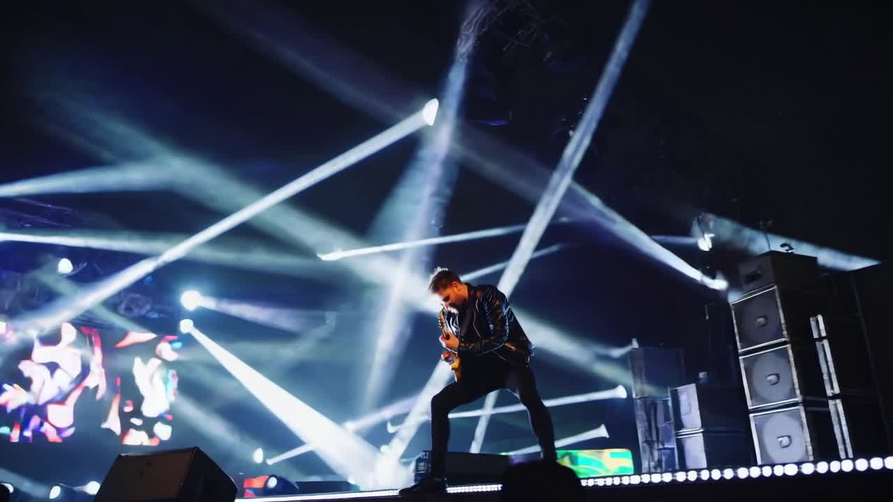 Guitarist performing energetically on stage, engaging with the audience while dynamic lights create an electrifying atmosphere, showcasing the excitement of a live music event