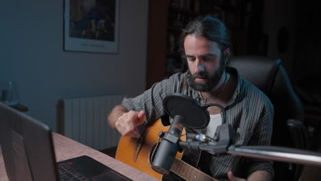 musician recording acoustic guitar in home studio
