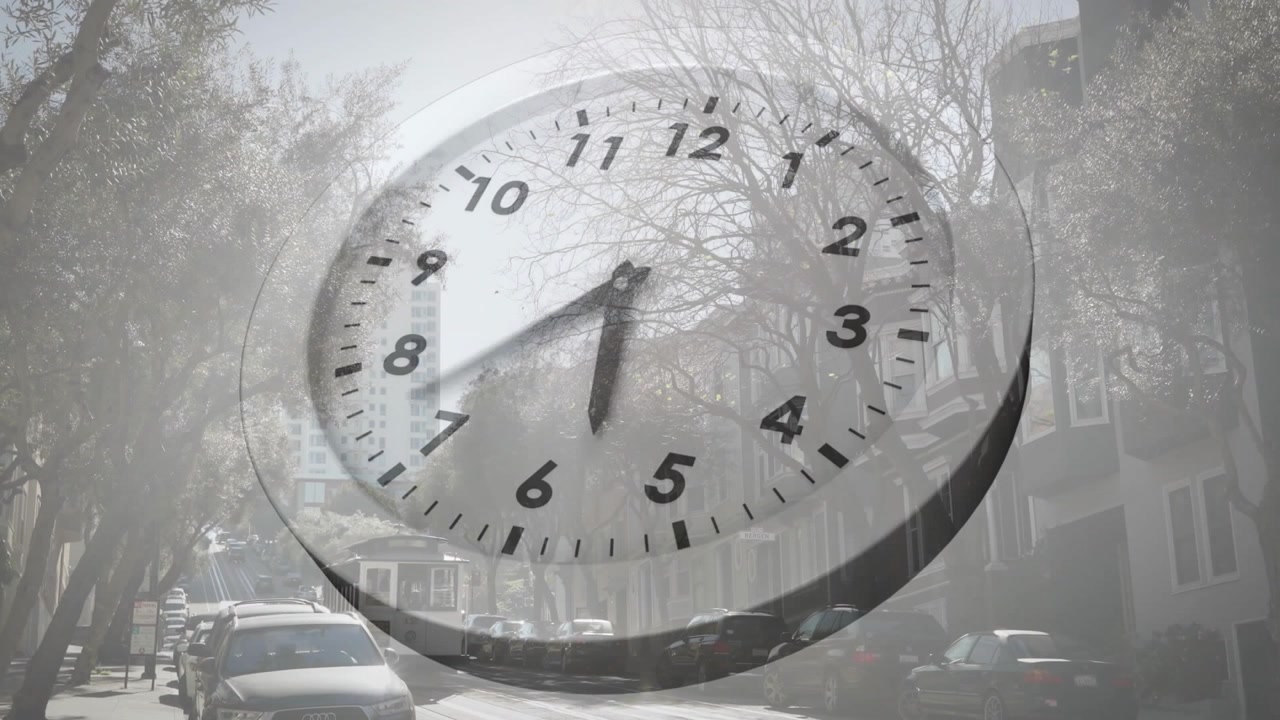 Quadrante di orologio analogico che sfuma in una vista stradale mentre le lancette ruotano rapidamente per illustrare il passare del tempo.