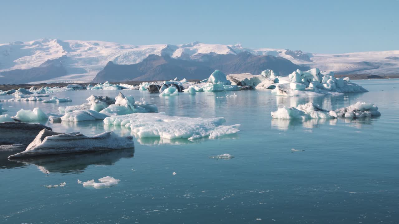 Icy cold still frozen sea lagoon in arctic landscape with mountains
