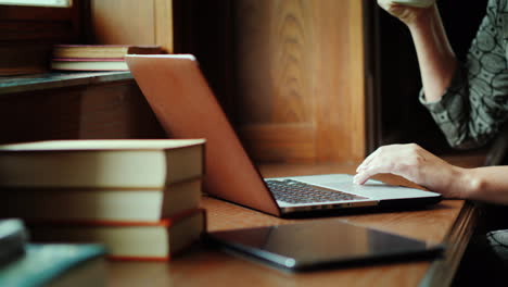 manos escribiendo en la computadora portátil con libros y café