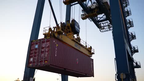 efficient loading and unloading of shipping container using crane technology in industrial port setting during sunset hours