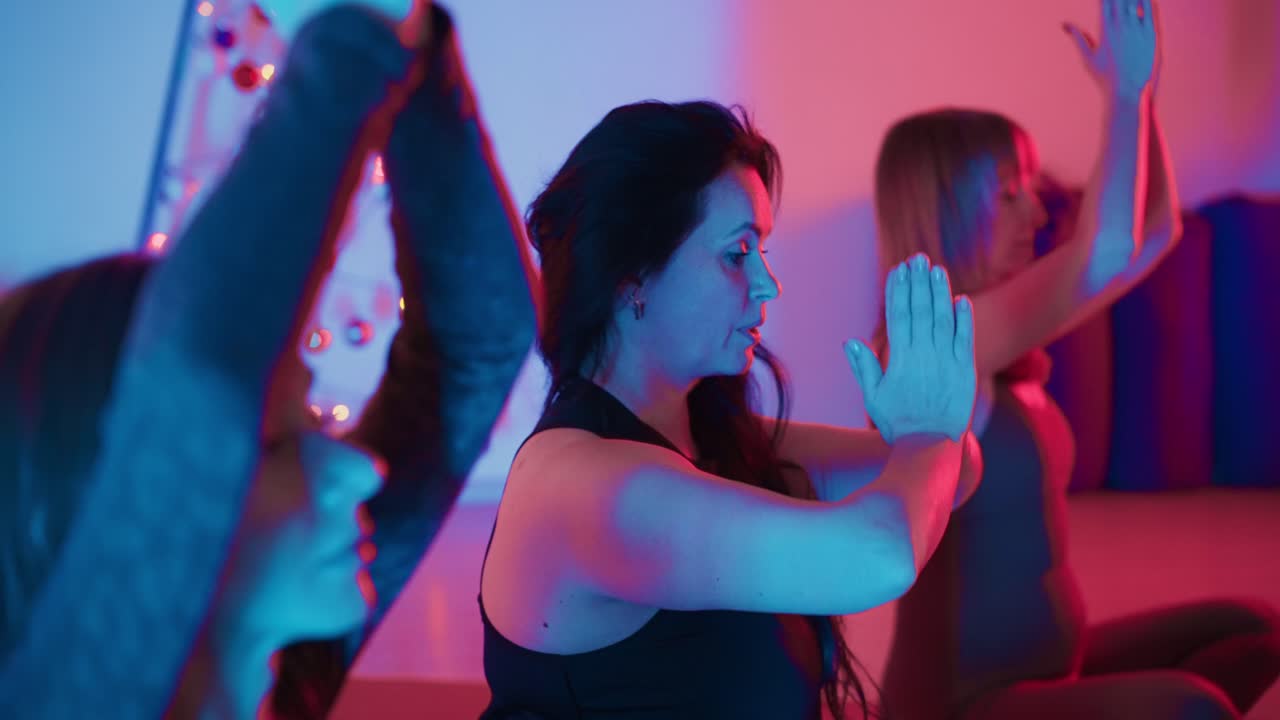 Women practicing yoga in a studio with vibrant lighting