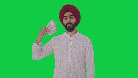 egoistic sikh indian man using money as fan with cunning smile green screen