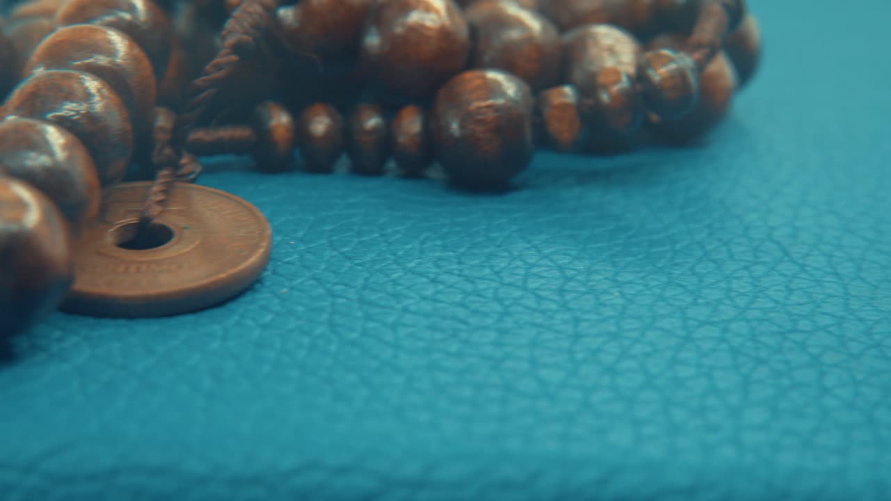 Macro pan shot of a wooden round beads necklace with coin medallion