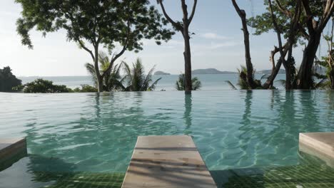 infinite-swimming-pool-with-background-of-natural-sea-and-mountain-view-with-some-tree