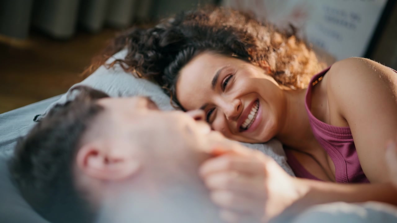 Close up loving woman caressing man face in bed. Happy couple bonding morning
