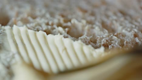 beautiful macro shot of margarine butter being spread on slice of bread with knife