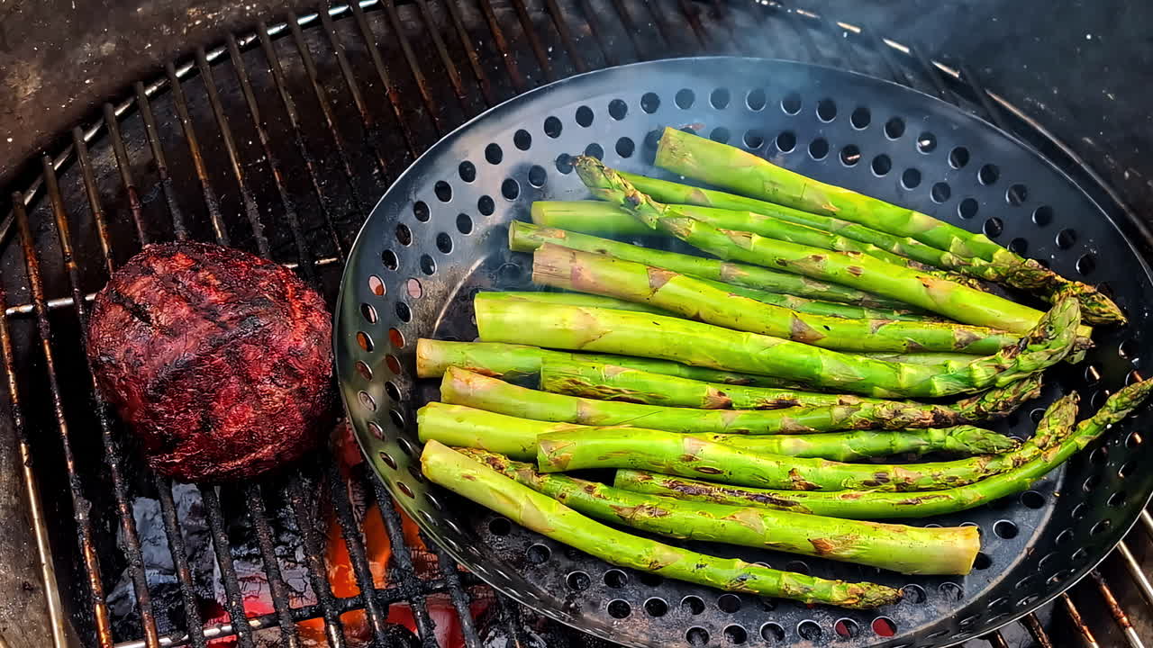 Assorted asparagus and vegetables on charcoal grill over open flame with smoke and crispy finish