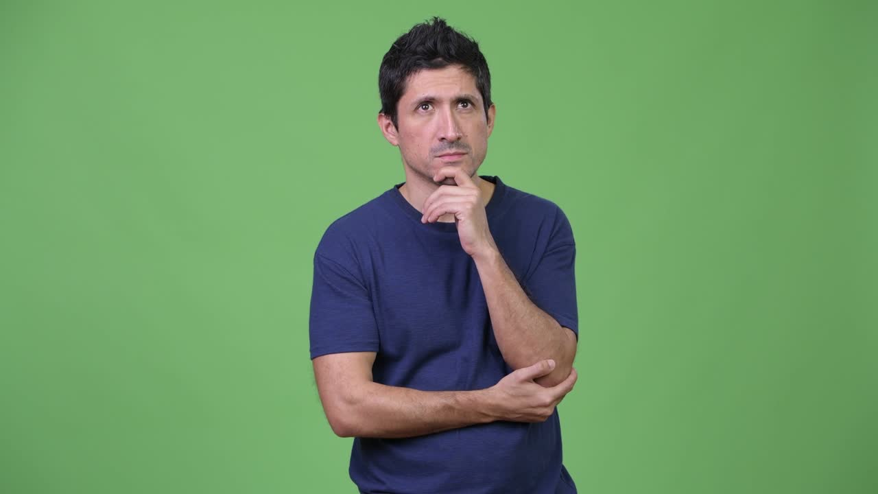 Hispanic man thinking against green background