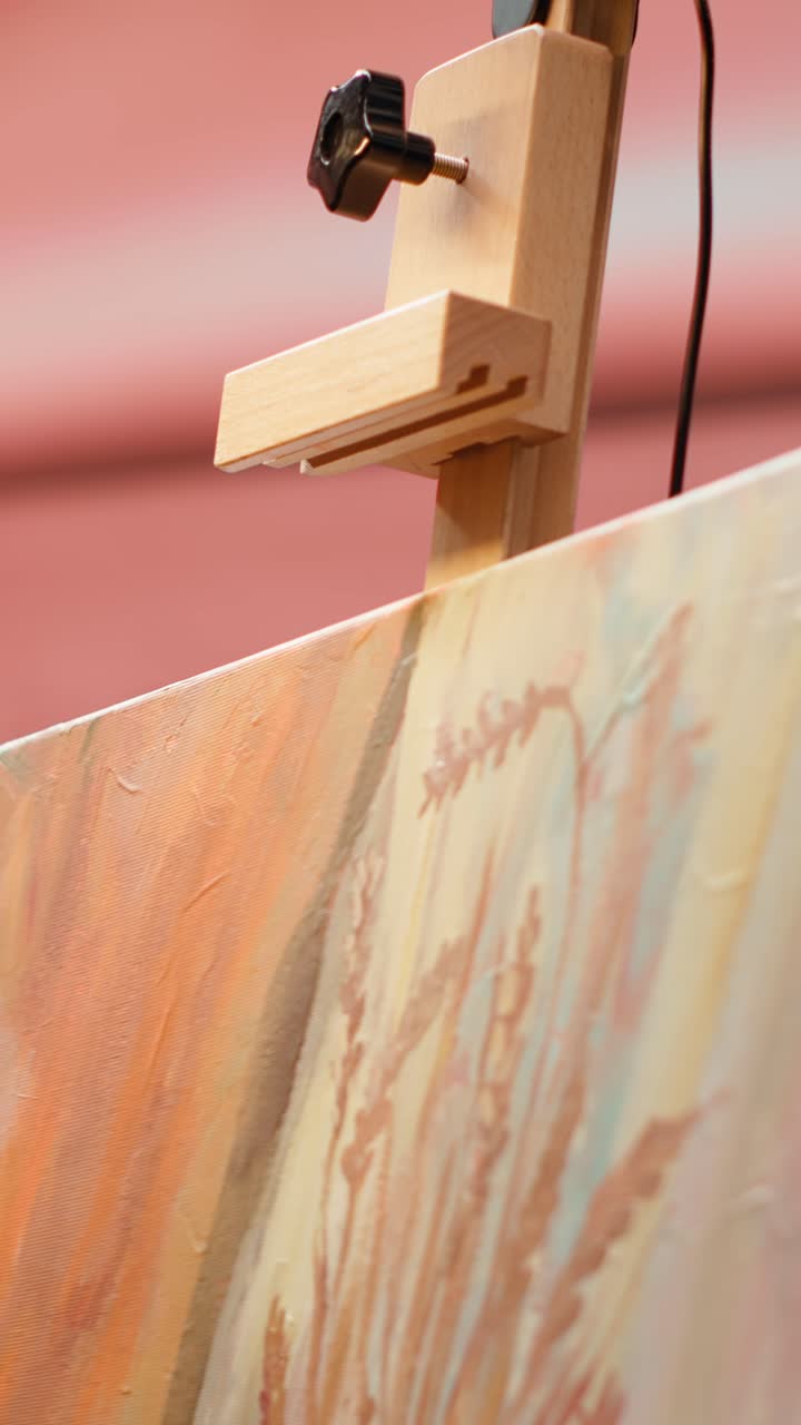 Artist's Hand Adjusting Canvas on a Wooden Easel