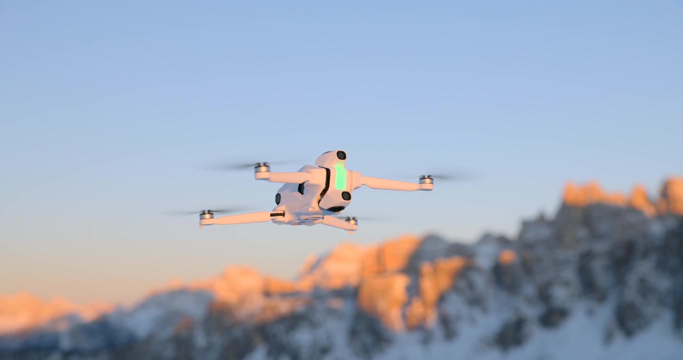 Drone quadricottero bianco in bilico a mezz'aria contro cime montuose innevate al tramonto dell'ora d'oro