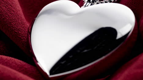 shiny silver heart locket on red fabric
