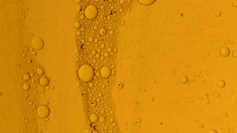 flujo de aceite dorado sucio con manchas negras lentamente con burbujas y polvo en la superficie