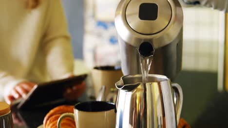 Lesbian-couple-preparing-coffee-and-using-digital-tablet-in-kitchen-4k