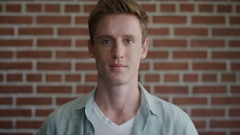 portrait happy young man smiling enjoying having fun cheerful red head male on brick wall background slow motion