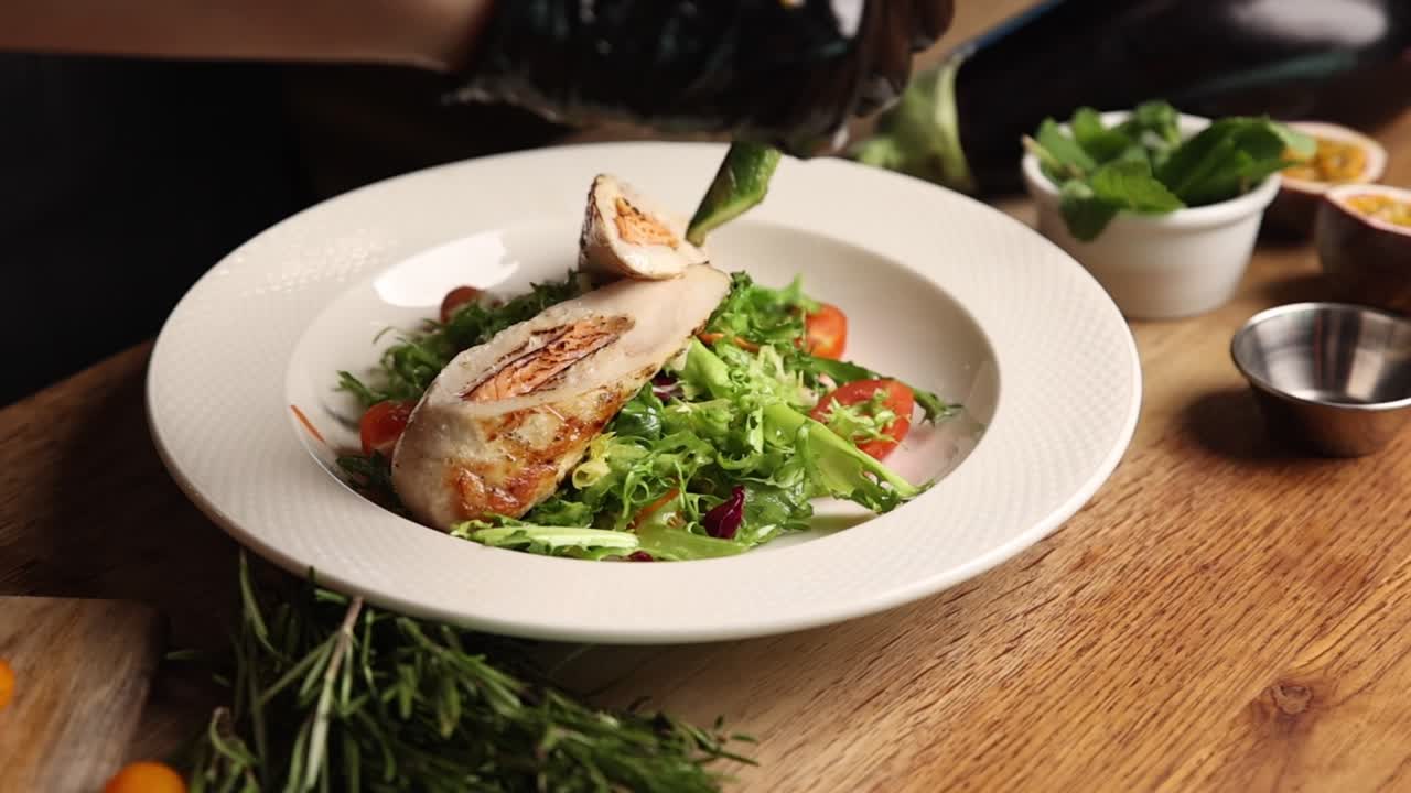 Chef che guarniscono un involtino di pollo con insalata fresca e asparagi
