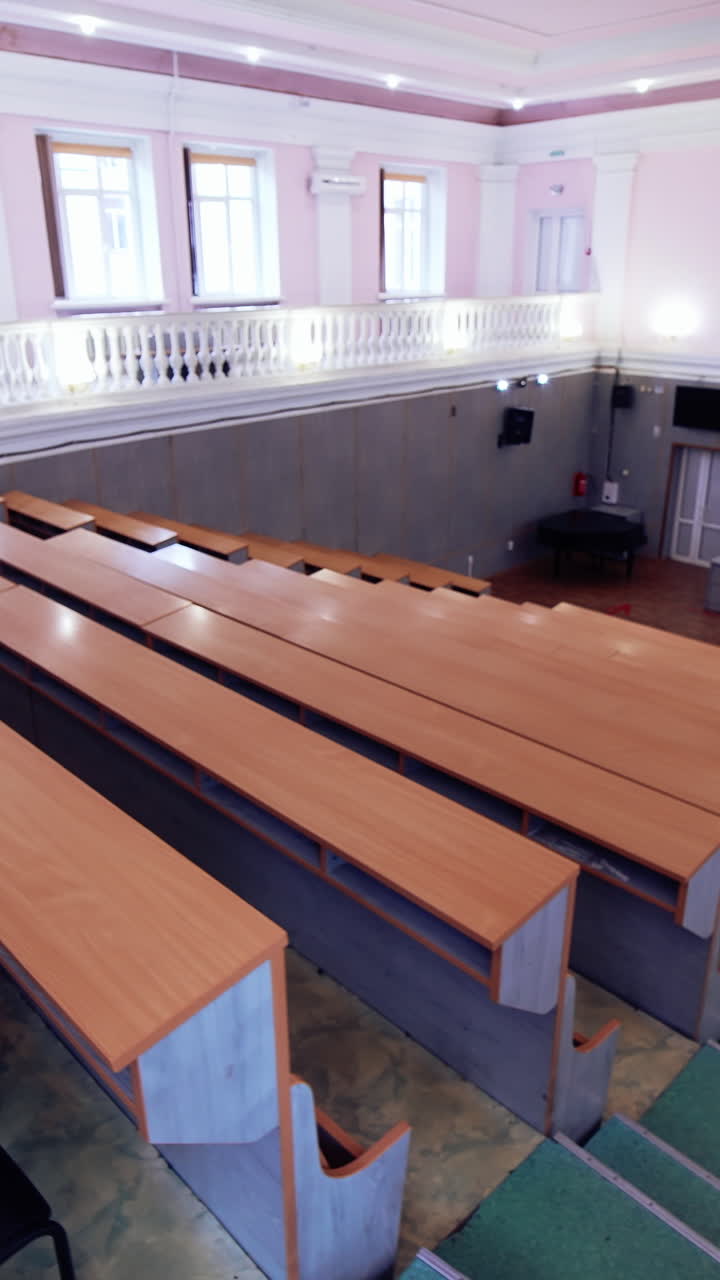 Large conference hall with nobody. Empty auditorium with large white board and rows of desks. Modern classroom for lectures in the university. Vertical video
