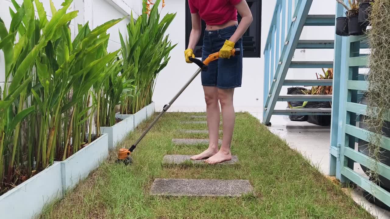 Woman trimming grass in backyard