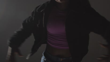 studio portrait shot of young woman dancing with low key lighting against grey background 7