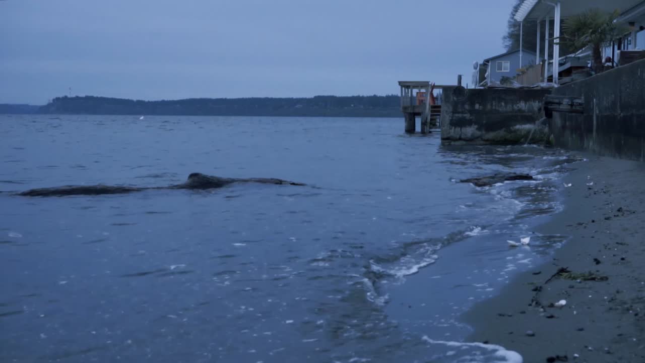 회색 하늘이 있는 선라이즈 비치의 래핑 파도