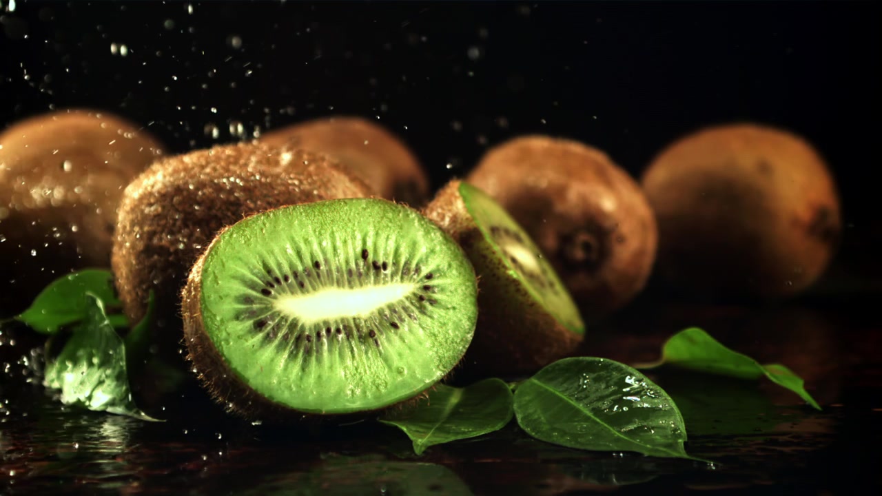 Rodajas de kiwi fresco con gotas de agua sobre fondo oscuro