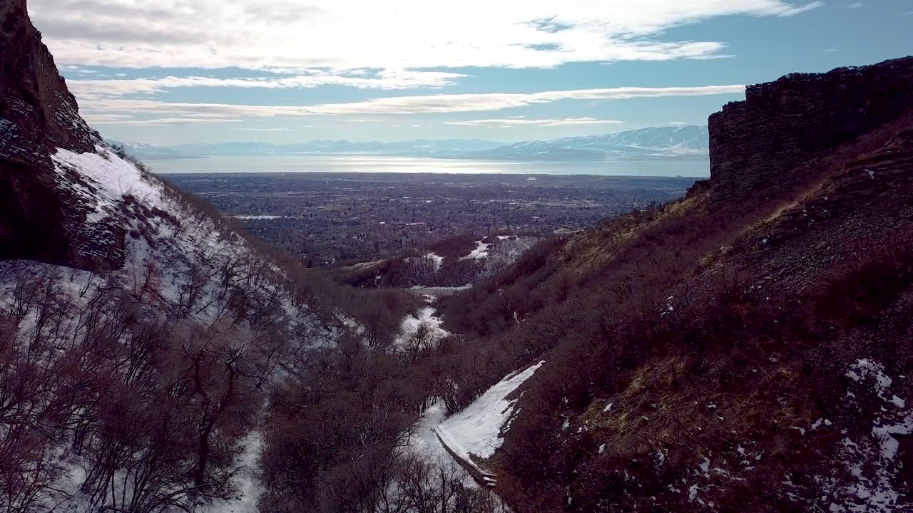 在兩座懸崖之間飛翔, 看到下面山谷中的城市, 有山和一個巨大的湖泊