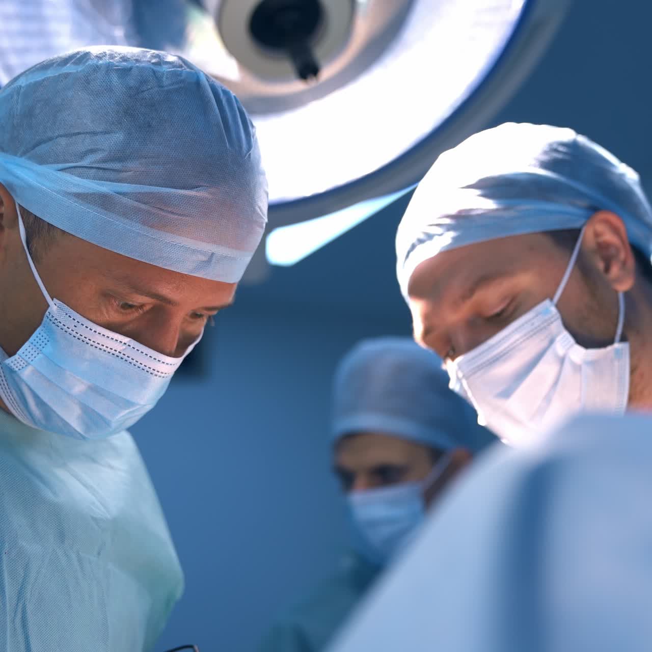 Realización de una cirugía plástica en una clínica moderna. Dos médicos inclinados sobre el paciente. Asistente al fondo, desenfocado.