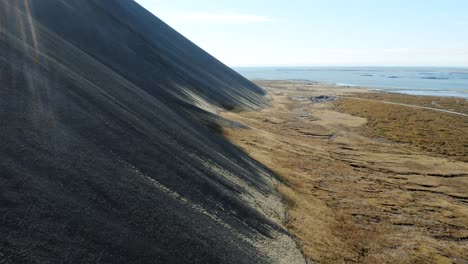 aerial along steep mountainside with black rocks - historic volcanic activity