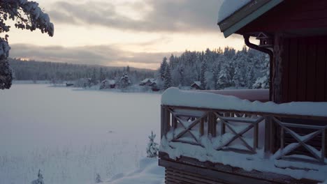 Idyllic-Village-In-Deep-Snow-Covered-Landscape-During-Sunset-With-Alaskan-Malamute-Dog-Breed-Walking-Outside