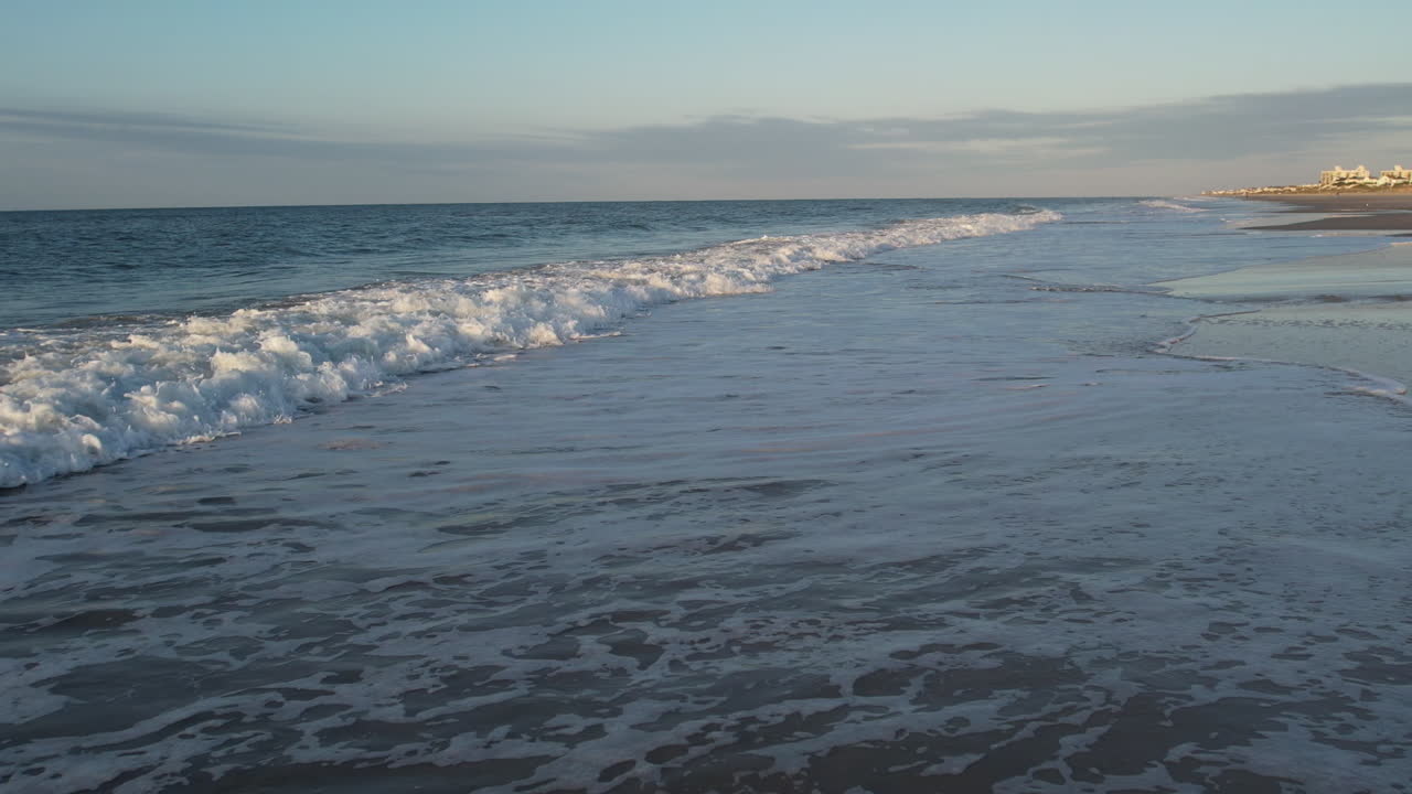 Drone che vola basso sopra le onde dell'oceano al rallentatore.