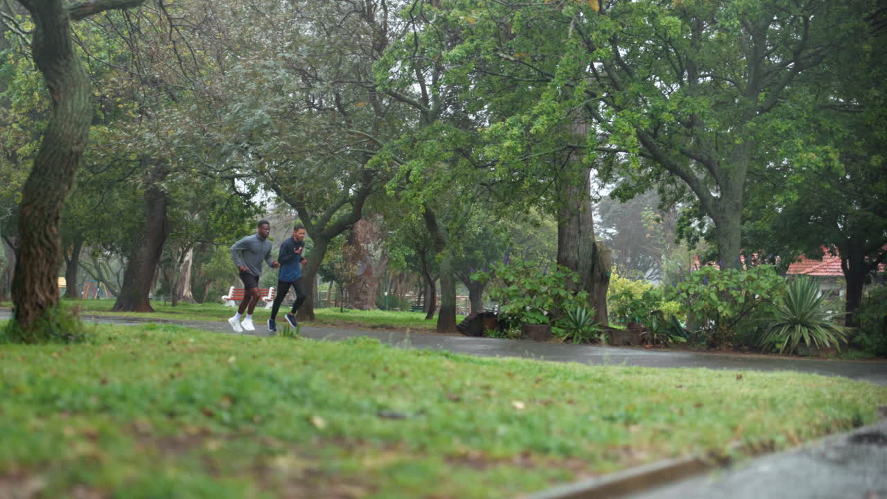 dos hombres corriendo en un parque en un día de lluvia