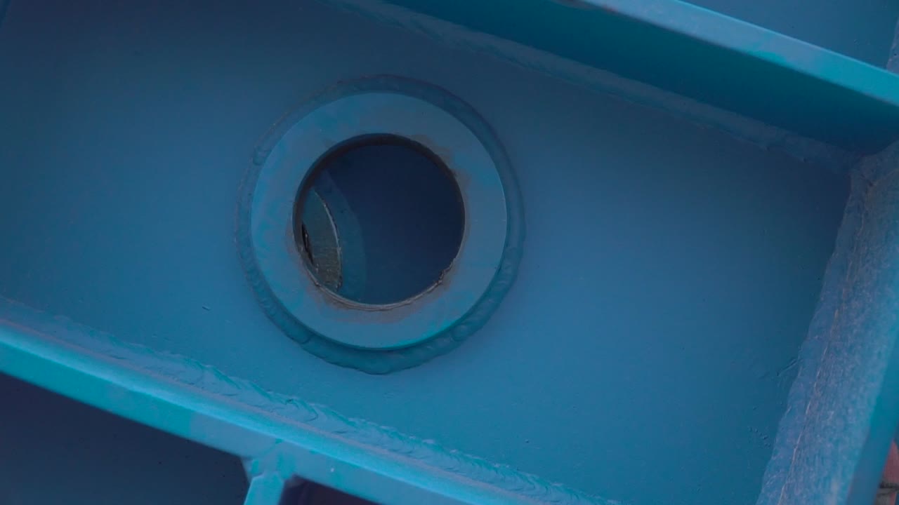 Close-up of a blue painted metal beam with a round hole and gasket
