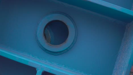 close-up of a blue painted metal beam with a round hole and gasket