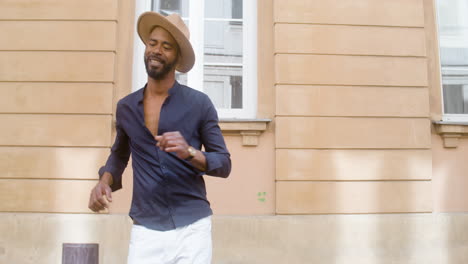 happy afro caribbean man with panama hat dancing latin choreographies alone in street 1