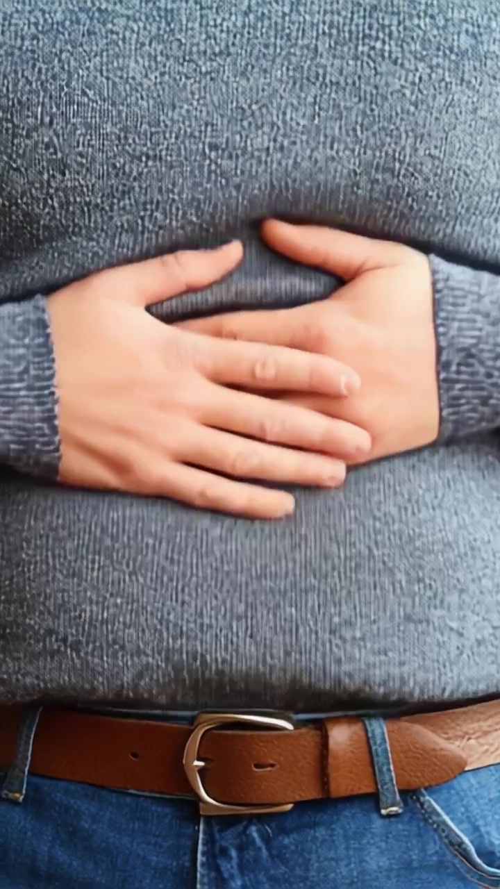 A Close-Up of a Person's Hands Resting on the Stomach, Showcasing a Relaxed yet Thoughtful Pose in Casual Knitwear