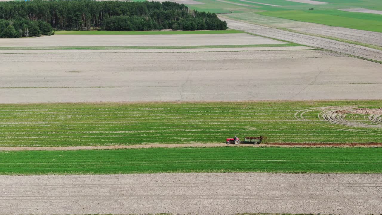 Tractor Works a Geometric Farmland Field in the Expansive Polish Countryside