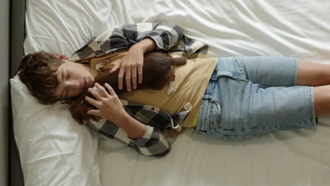 teenager cuddling a small dog on a bed