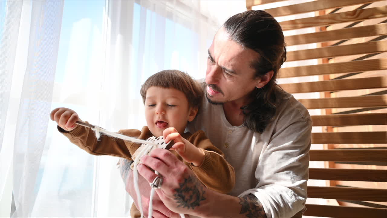 Father playing with his son with ecological wooden toys near the window