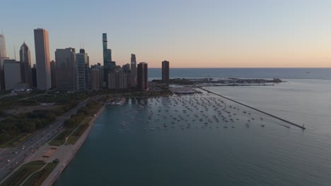 the chicago skyline glows as the sun rises over lake michigan