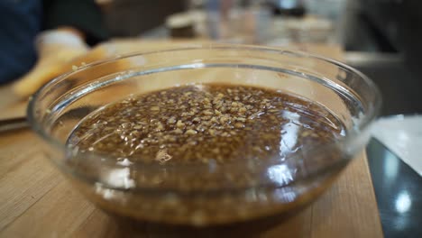 minced garlic and is being transported by a sharp knife to a small clear glass bowl.