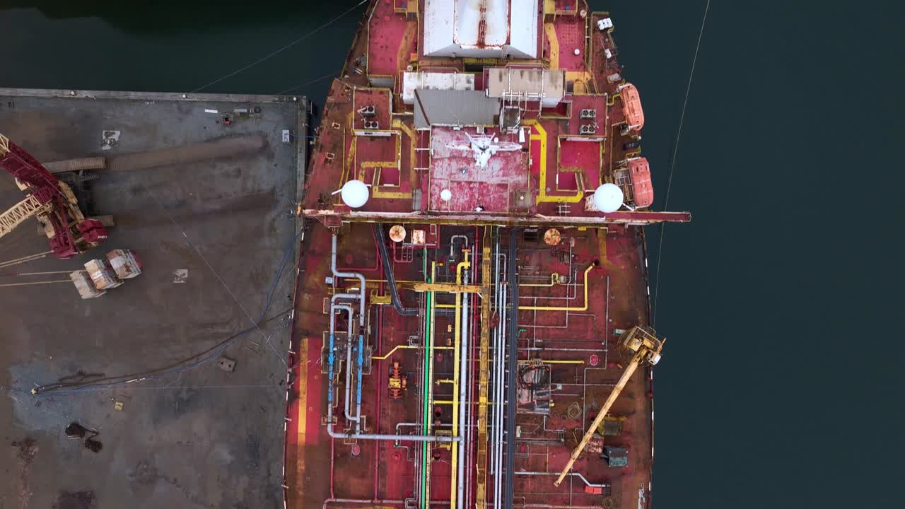 Drone footage of a weathered tanker deck from above, showing rust-covered industrial equipment, valves, and pipelines