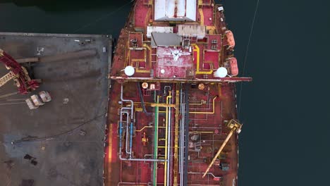 drone footage of a weathered tanker deck from above, showing rust-covered industrial equipment, valves, and pipelines