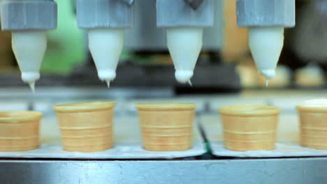 ice cream pouring in waffle cones. automated production line at food factory