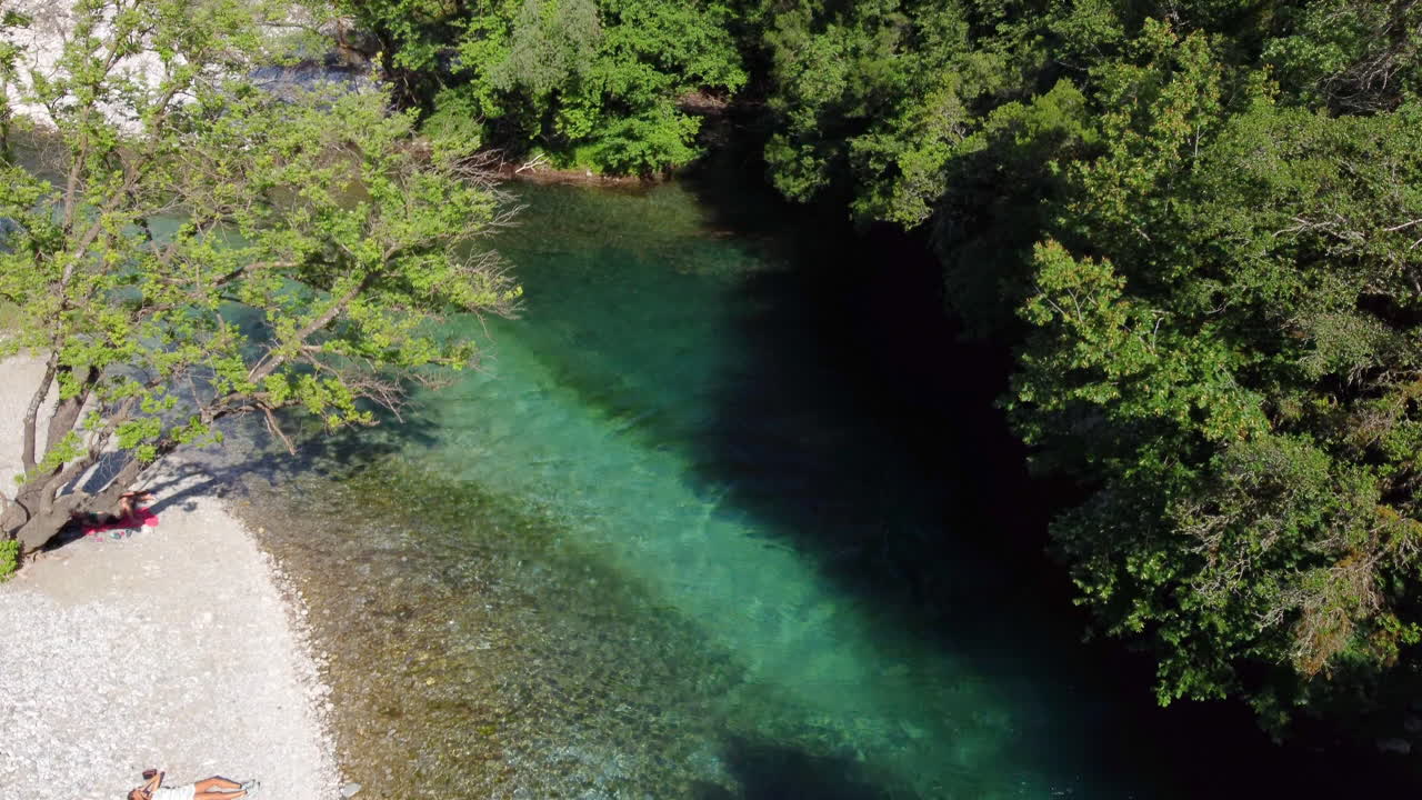 Una donna si gode il sole sdraiata sulla sponda ghiaiosa del famoso fiume Voidomatis, che scorre attraverso il Parco Nazionale di Vikos in Epiro, Grecia.