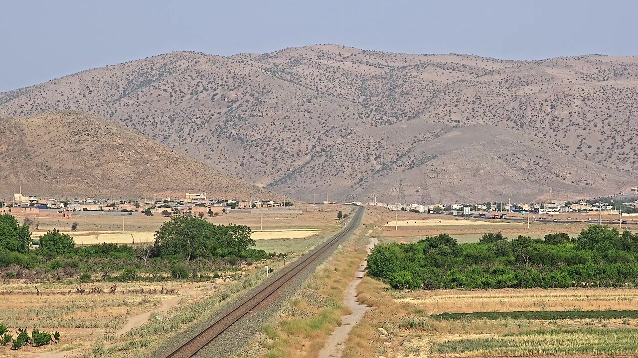 Binari ferroviari che conducono verso montagne lontane in un paesaggio rurale