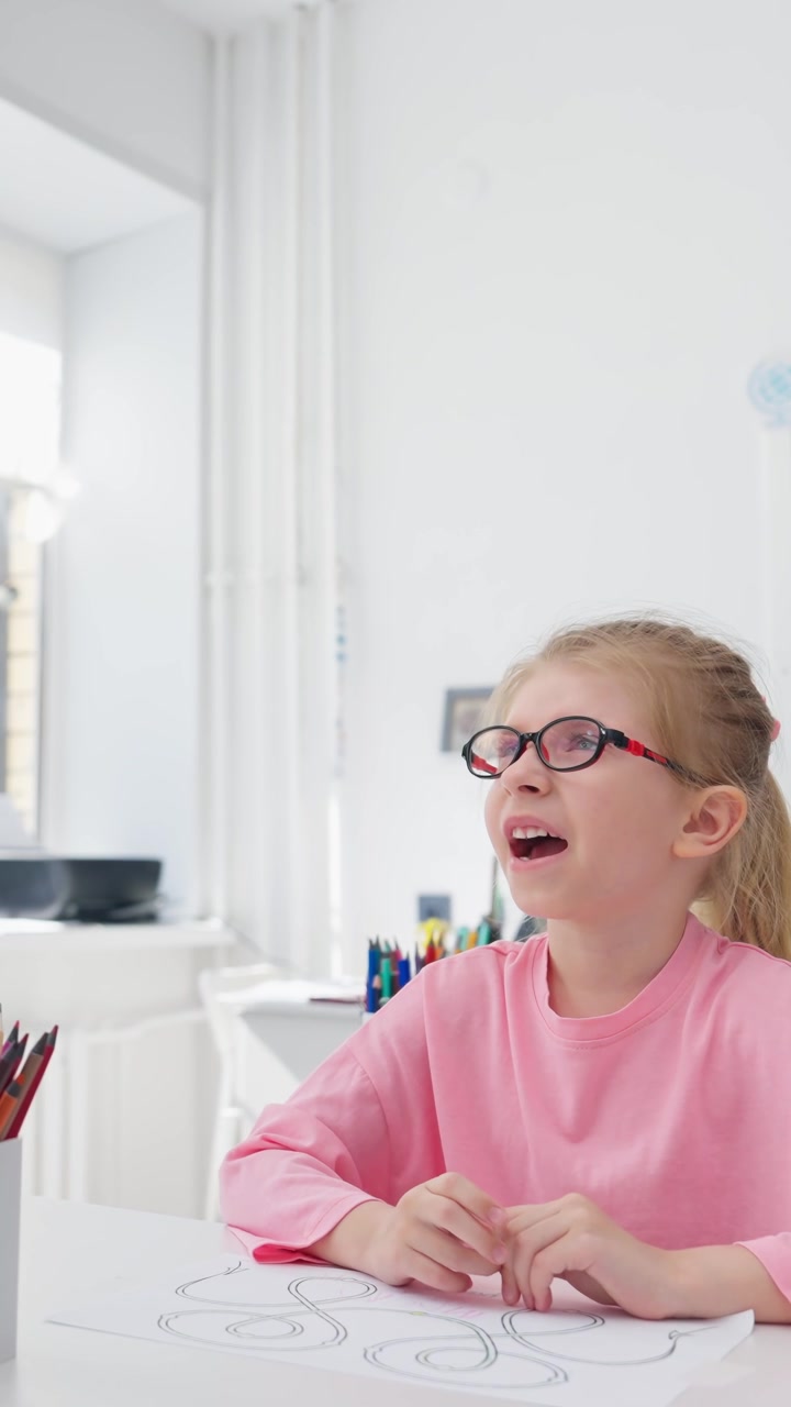 Giovane ragazza felice con gli occhiali che impara in un'aula luminosa.