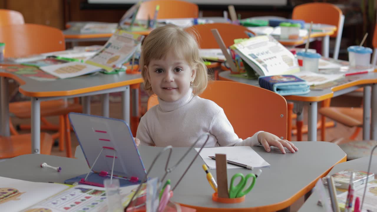 Girl drawing at the table in classroom. Education. Child sitting at a desk