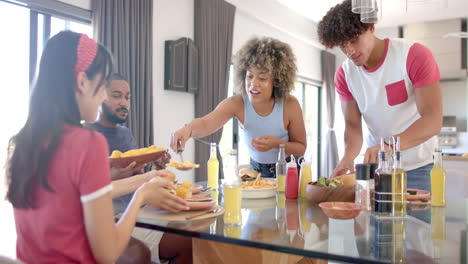 diverse friends sharing food and drinks around dining table, enjoying time together